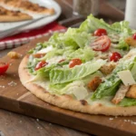 A freshly prepared chicken crust Caesar salad pizza topped with romaine lettuce, cherry tomatoes, Parmesan cheese, and a drizzle of Caesar dressing, highlighting low-calorie and keto-friendly benefits