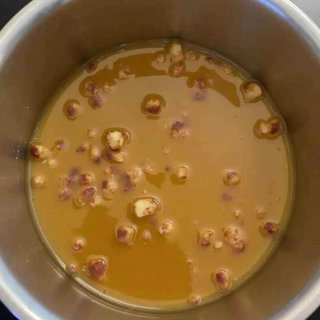 A saucepan containing melted butter and browned bits, resembling the preparation of a caramel-like base.