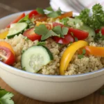 A bowl of cooked organic quinoa with fresh vegetables and herbs.